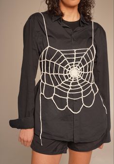 a woman wearing a spider web shirt and shorts