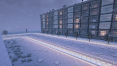 a large building that is next to a snow covered field with lights on the ground