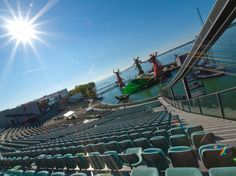 the sun shines brightly in front of an empty stadium filled with blue chairs and green seats