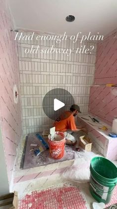 a man is working in the bathroom with pink tiles on the walls and flooring