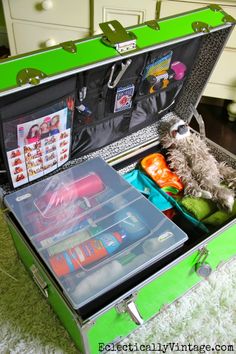 an open suitcase filled with toys and other items on top of a carpeted floor