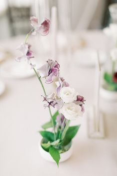 flowers in a vase on a table with other place settings and dishes to the side