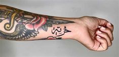 a person's arm with tattoos on it and an arabic writing in the middle