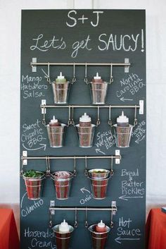 a chalk board with some cups and sauces hanging from it's sides on the wall