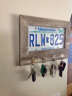 a license plate mounted to a wall with keys hanging from it's hooks,