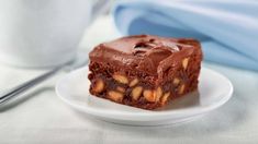 a piece of brownie on a plate next to a cup