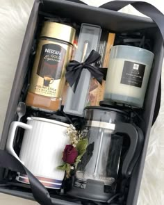 an open box containing coffee, candles and other personal care items on a white furnishing