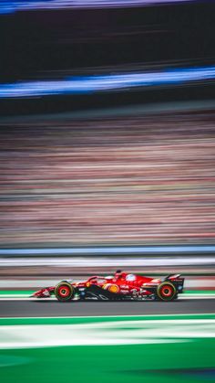 a red race car driving down a track with blurry lines on the side of it