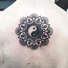 a man with a tattoo on his back has a yin - yang symbol in the center