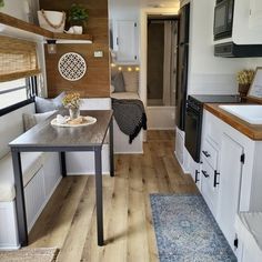 the interior of a tiny home with wood flooring and white cabinets, along with an open kitchen area