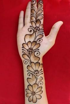 a woman's hand with a henna tattoo on it, and an intricate flower design