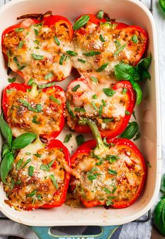 stuffed bell peppers in a casserole dish with basil