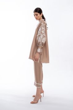 A tan rawsilk shirt features floral appliqué work on gathered sleeves and scallop detailed edges. Paired with matching rawsilk culottes. Model Height is 5'10 and Shirt Length is 33'