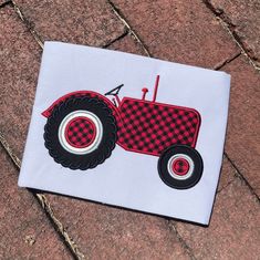 a red and black tractor on a white background is embroidered onto a piece of fabric