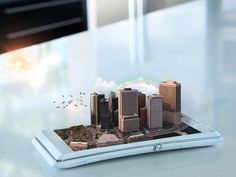 an image of a tablet with buildings and birds flying over it on a table in front of a window