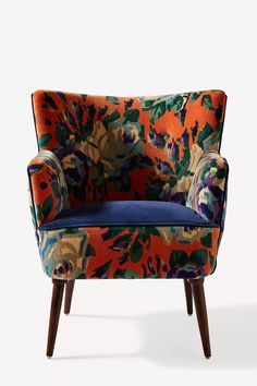 an orange and blue floral chair with wooden legs