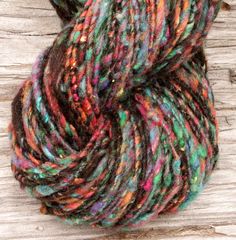 a skein of multicolored yarn sitting on top of a piece of wood