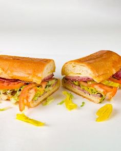 two sandwiches cut in half sitting on top of a white surface with yellow and red confetti