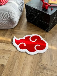 a red and white rug sitting on top of a wooden floor next to a black box