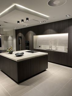 a large kitchen with an island in the middle and lights above it, along with two sinks