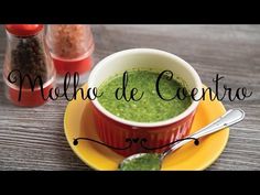 a bowl filled with green liquid sitting on top of a yellow plate next to spices