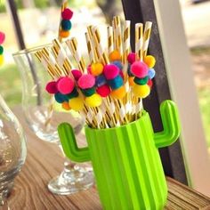 a green vase filled with pom - poms on top of a wooden table