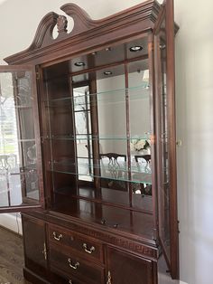 a wooden china cabinet with glass doors and drawers on the front, in a living room