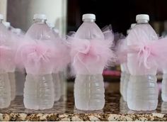 three plastic water bottles with pink tulle bows on them sitting on a marble counter