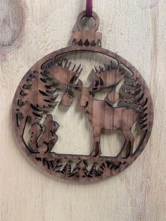 a wooden ornament with deer and moose in the woods on a wood background