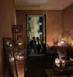 two people sitting on a couch in a living room next to a doorway with candles