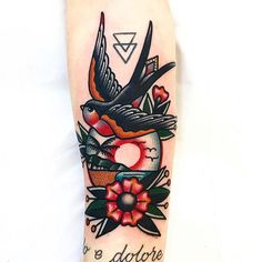 a tattoo on the arm of a woman with flowers and a bird flying over it