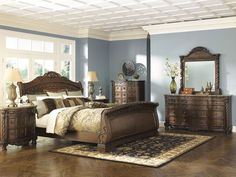 a bedroom scene with focus on the bed, dressers and mirror in the room