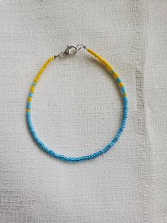 "I reccomend that you measure your ankle and send me the length desired in a note or message. That way I can tailor the length to your personal specifications. If you do not notify me of the size needed, you will get the size selected at checkout with a 2\" extender chain. This anklet is made with light blue, turquoise, and sunshine yellow seed beads. They are strung onto beading wire and finished with a silver color lobster claw clasp and two inch extender chain. Size Options: 8\" adjustable to Blue Beaded Chain Bracelets For Beach, Casual Yellow Beads For Beach, Beaded Bracelets For Beach Festival With Tiny Beads, Blue Bracelet Anklets For Beach, Adjustable Colorful Beaded Strand Anklets, Yellow Beaded Bracelets For Beach With Colorful Beads, Yellow Beaded Bracelets With Colorful Beads For Beach, Colorful Beaded Bracelets For The Beach, Beach Heishi Beaded Bracelets