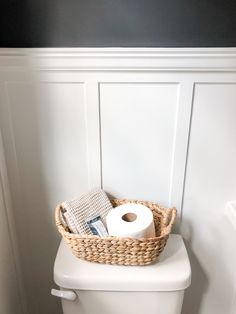 a toilet with a basket on top of it next to a toilet paper dispenser