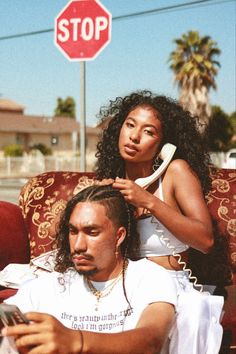 a man sitting next to a woman on top of a couch under a stop sign