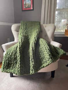 a green blanket sitting on top of a white chair