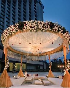 an outdoor wedding setup with white flowers and chandelier on the ceiling, in front of a tall building