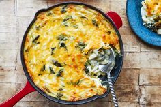 a casserole with spinach and cheese in a red pan on a wooden table