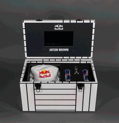 an open cooler with two cans and a hat in it's lid, on a grey background