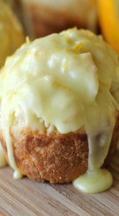 a muffin covered in icing sitting on top of a wooden cutting board