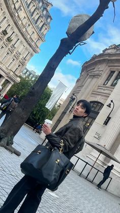 a woman standing on the street holding a coffee cup