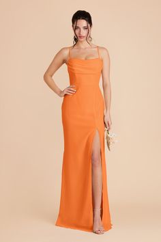 a woman in an orange dress posing for the camera with her hands on her hips