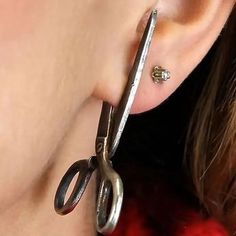 a close up of a person wearing some kind of earring with scissors attached to it