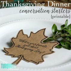 a white plate topped with a leaf shaped place card on top of a wooden table