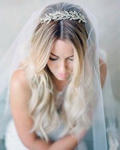 a woman wearing a veil with a tiara on her head and holding a wedding bouquet