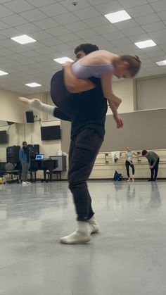 a man and woman are dancing in an empty dance studio while others watch from the sidelines