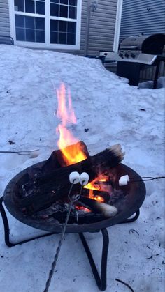 an open fire pit sitting on top of snow covered ground