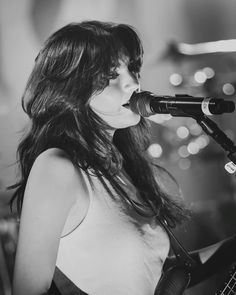 a woman singing into a microphone while holding a guitar