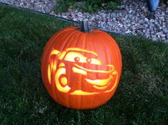 a pumpkin carved to look like a car is sitting in the grass with it's headlights turned on