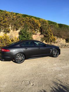 a black car parked in front of a hill